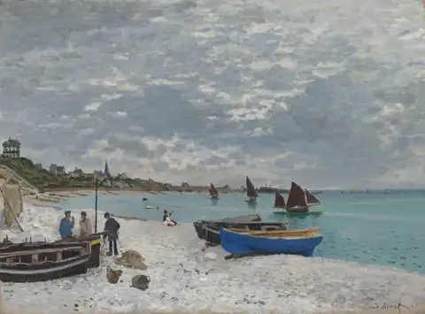 Fishing boats pulled up on a pebble beach under a wide gray sky, with sailboats on the water.