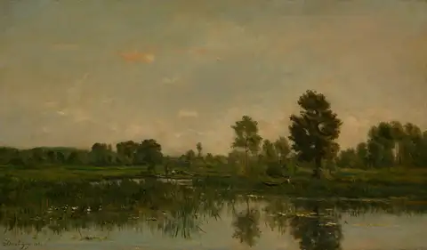 A still marsh at the end of the day, with tall trees and reeds reflected in the water under a soft sky.